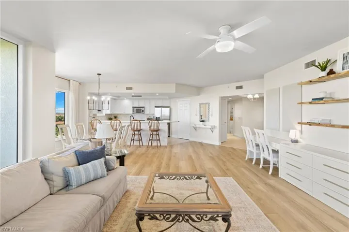 Living room with a chandelier, light wood finished floors, and ceiling fan