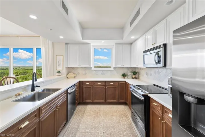 Kitchen featuring stainless steel appliances, recessed lighting, white cabinetry, backsplash, and granite tiled floors