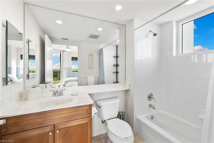 Ensuite bathroom featuring shower / bath combination with curtain, recessed lighting, vanity, and light tile patterned floors