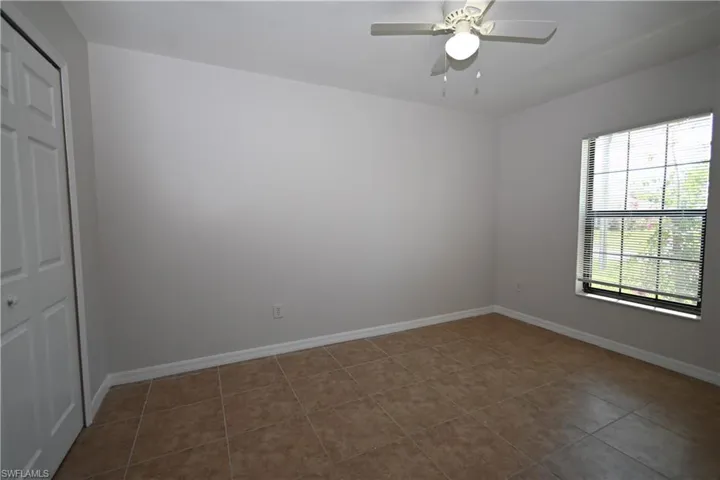 Room with tile flooring, light-toned walls, and a ceiling fan with integrated lighting