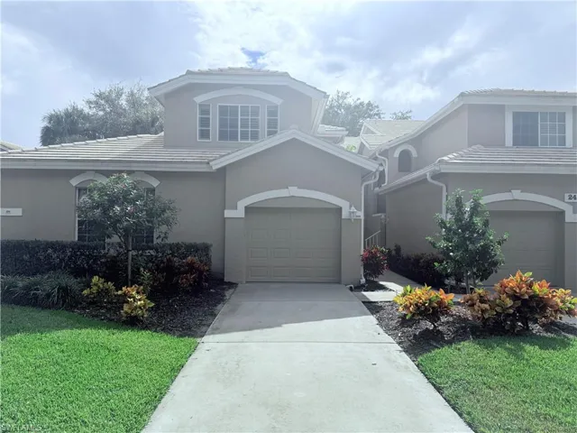 Traditional-style house with driveway, a garage, stucco siding, a front lawn, and a tile roof