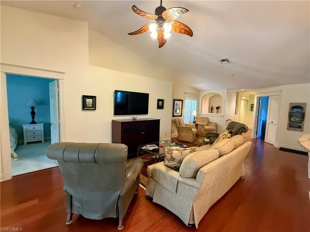 Living room with lofted ceiling, wood finished floors, and ceiling fan