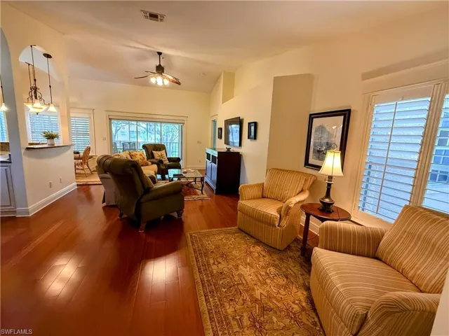 Living room with vaulted ceiling, hardwood / wood-style flooring, ceiling fan, and plenty of natural light