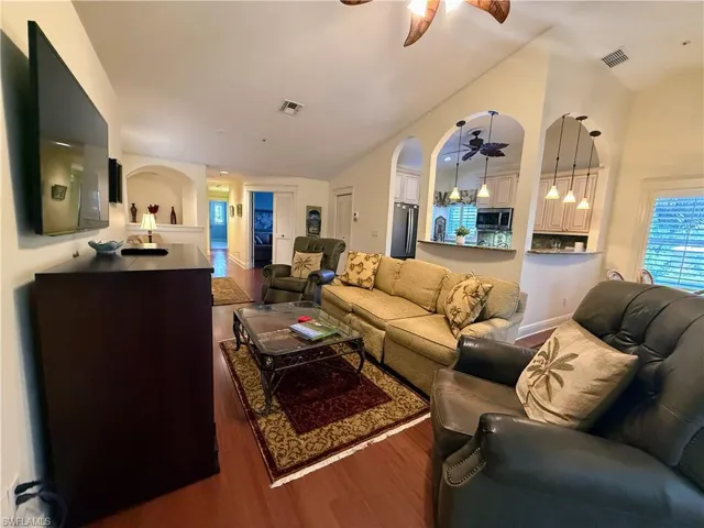 Living room featuring dark wood finished floors, lofted ceiling, a ceiling fan, and healthy amount of natural light