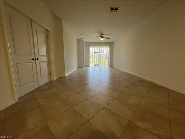 Empty room with light tile patterned flooring, baseboards, a ceiling fan, and visible vents