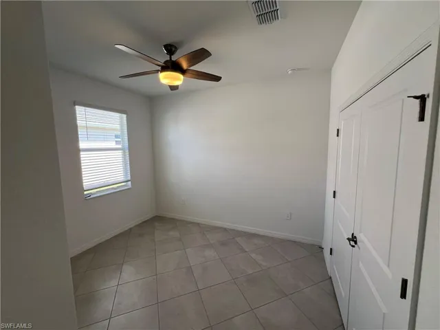 Empty room featuring visible vents, ceiling fan, baseboards, and light tile patterned floors