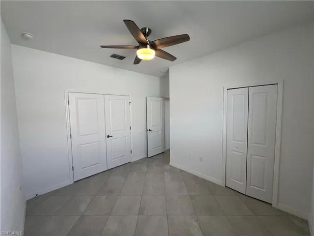 Unfurnished bedroom with light tile patterned floors, baseboards, a ceiling fan, and visible vents