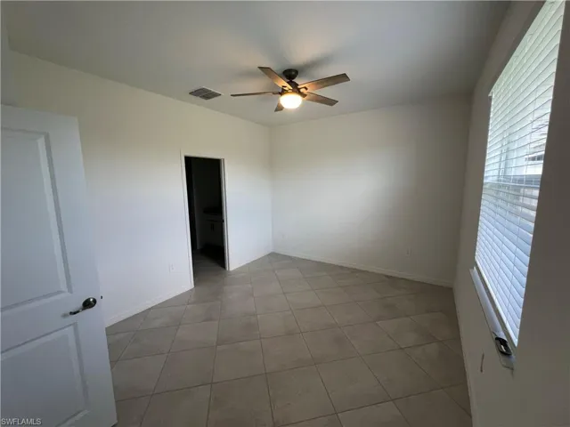 Tiled spare room with visible vents, ceiling fan, and baseboards