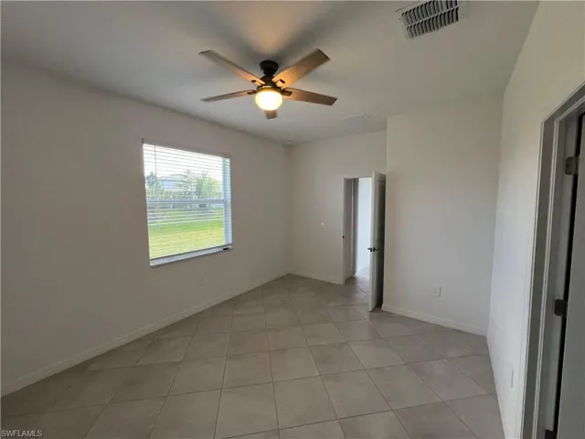 Spare room with light tile patterned floors, baseboards, a ceiling fan, and visible vents