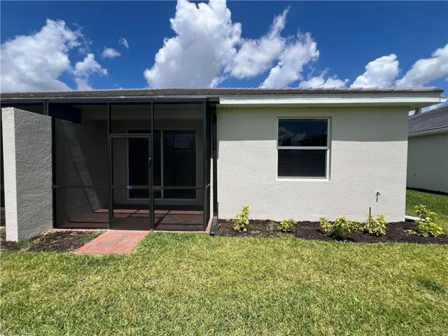 Back of house featuring a lawn, stucco siding, and a sunroom