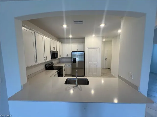 Kitchen with a sink, electric range oven, stainless steel fridge with ice dispenser, visible vents, and recessed lighting