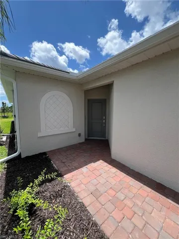 View of exterior entry featuring stucco siding and a patio area