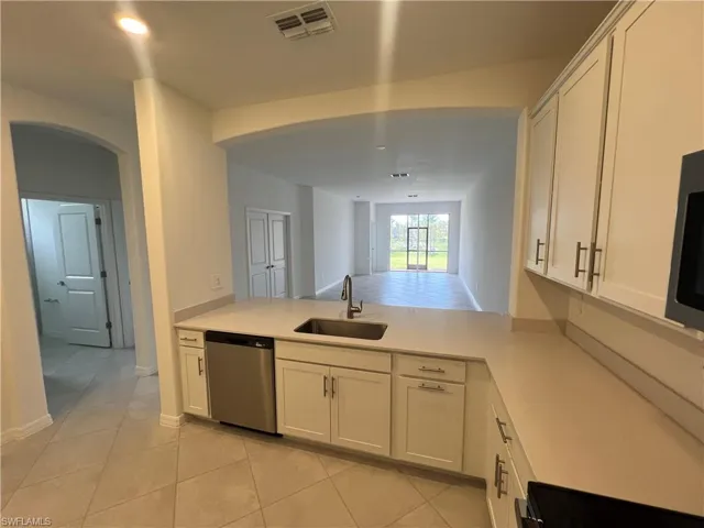 Kitchen with light countertops, a sink, appliances with stainless steel finishes, a peninsula, and visible vents
