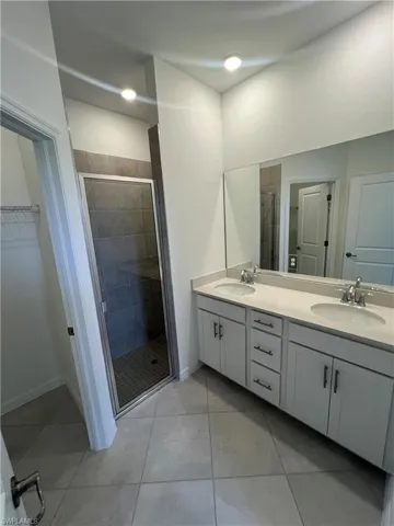 Bathroom with double vanity, a sink, and a stall shower