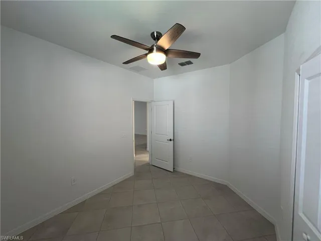 Unfurnished room featuring ceiling fan, baseboards, visible vents, and light tile patterned floors