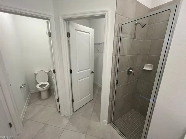 Full bathroom with baseboards, toilet, and a shower stall