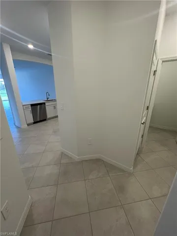 Corridor with baseboards, a sink, and light tile patterned floors
