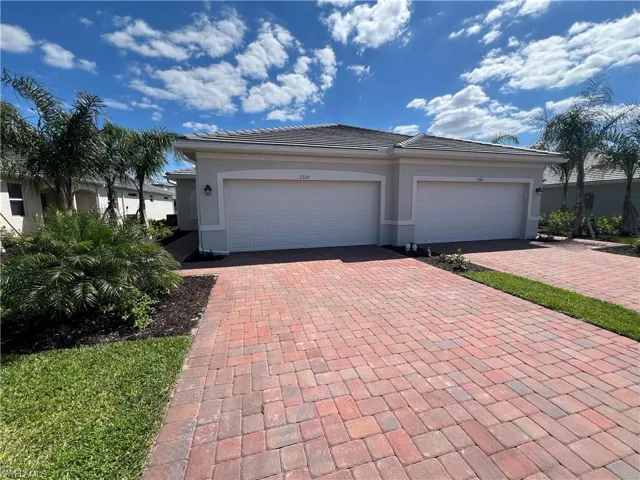 View of front of house with a tiled roof, an attached garage, decorative driveway, and stucco siding