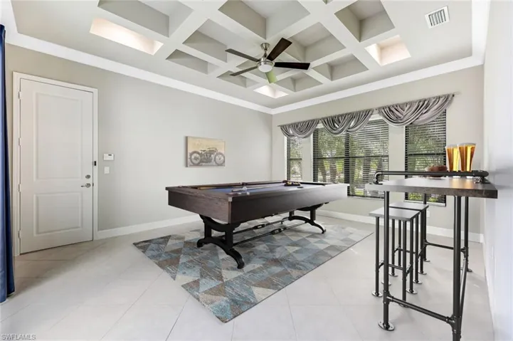 Virtual staged Den/game room Rec room with billiards table, coffered ceiling, light tile patterned floors, ceiling fan, and beamed ceiling