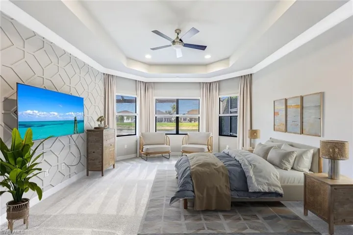 Virtual staged primary bedroom featuring an accent wall, a raised ceiling, ceiling fan, recessed lighting, and wallpapered walls