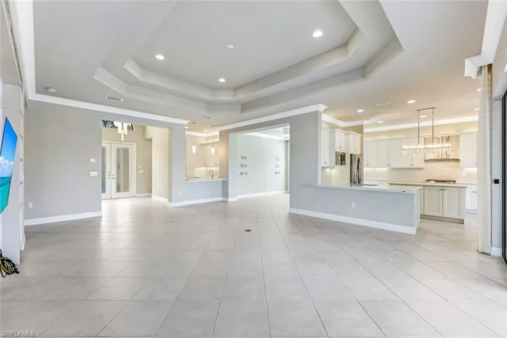 Unfurnished living room with light tile patterned floors, recessed lighting, a chandelier, french doors, and crown molding