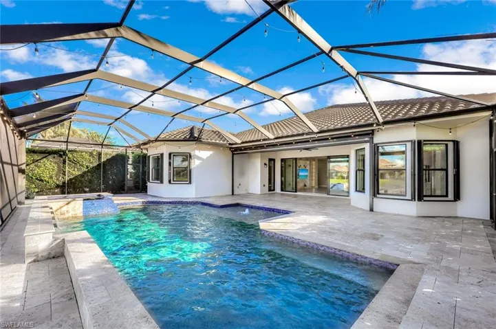 View of swimming pool featuring glass enclosure, a patio area, a water view, a sunroom, and a pool with connected hot tub