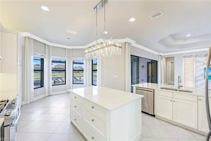 Kitchen with a chandelier, stainless steel appliances, wall chimney range hood, a peninsula, and tasteful backsplash