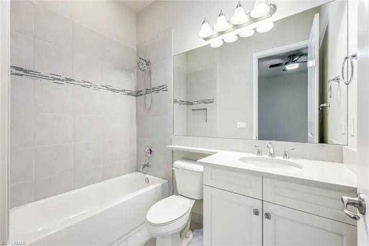 Bathroom with vanity, a ceiling fan, and light tile