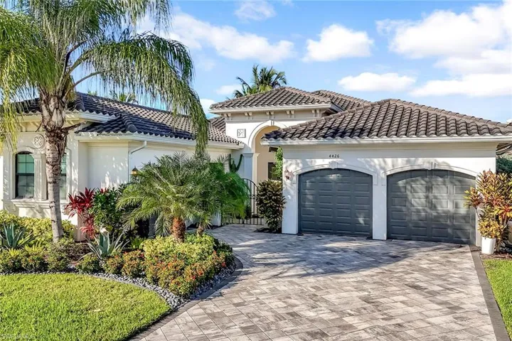 Mediterranean / spanish home featuring a tile roof, stucco siding, an attached garage, and decorative driveway