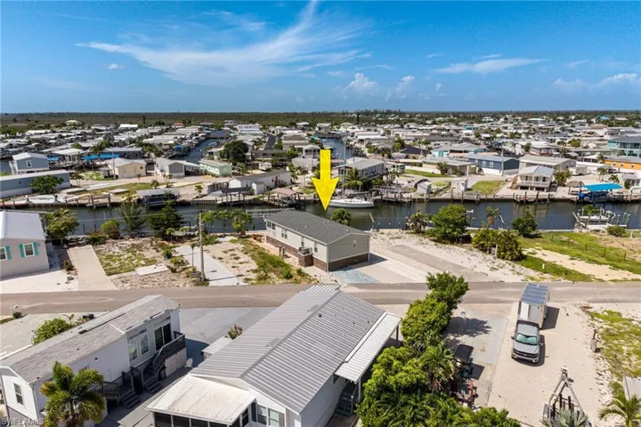 Waterfront property featuring a canal, private dock, and a single-story residence with a shingle roof.