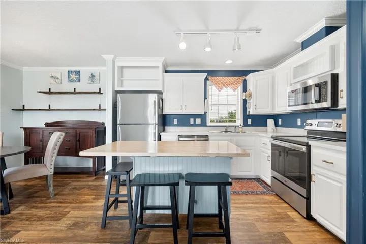 Kitchen featuring a light wood-finish flooring, white cabinetry, and stainless steel appliances great for entertaining.