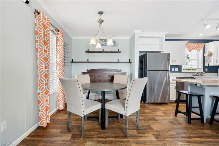 Open-concept dining area with wood-finish flooring, a contemporary chandelier, and integrated shelving. Great for entertaining your guests.