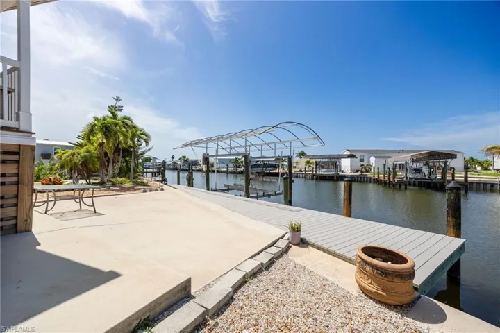 Waterfront property featuring a composite dock, 8k lb boat lift with canopy, concrete patio, and a gravel hardscape area.