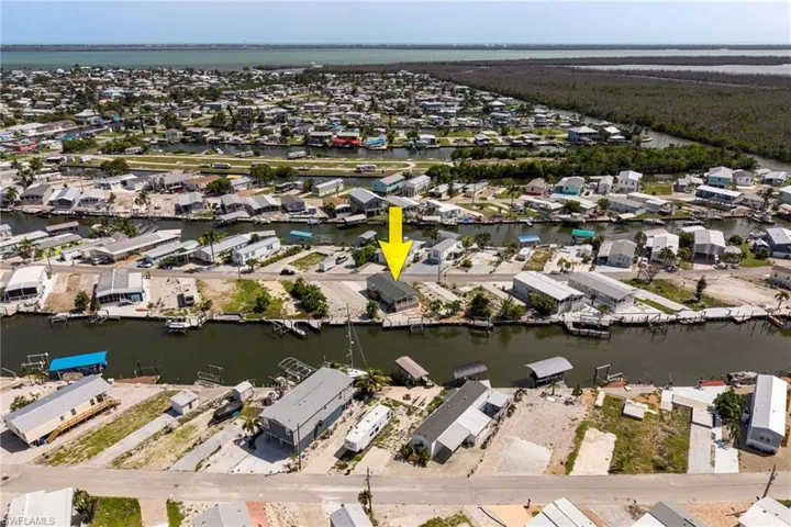 Waterfront property featuring direct gulf access, a boat lift, and surrounding coastal landscape.