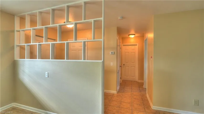 Built-in open shelving partition with neutral-toned walls and tile flooring