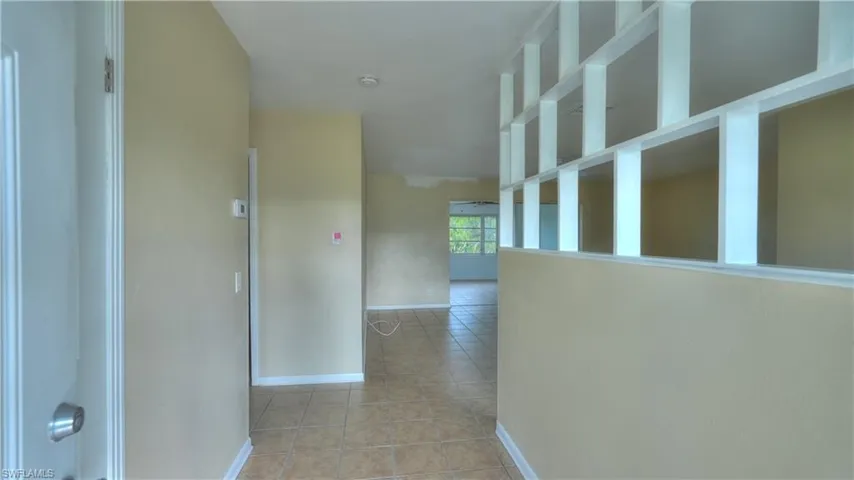 Interior features a decorative half-wall with open shelving, neutral wall tones, and tile flooring
