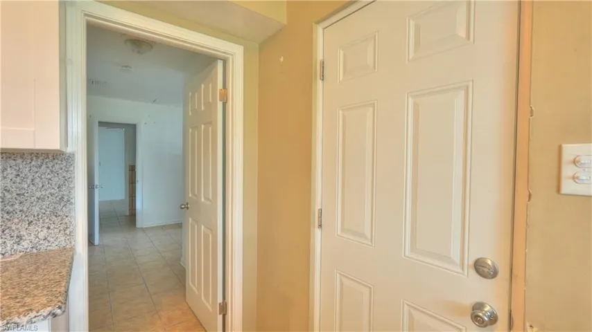 Kitchen countertop with a speckled stone finish, white upper cabinetry, and a white paneled door