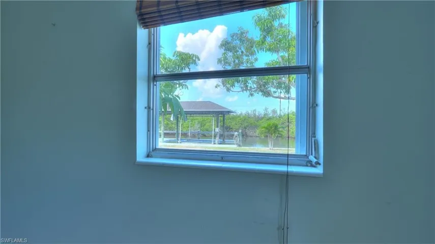 Interior window with a wooden blind overlooking a waterfront gazebo