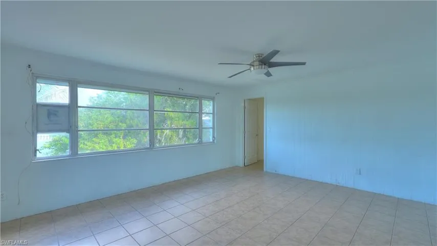 Spacious room featuring large windows, tile flooring, and a ceiling fan