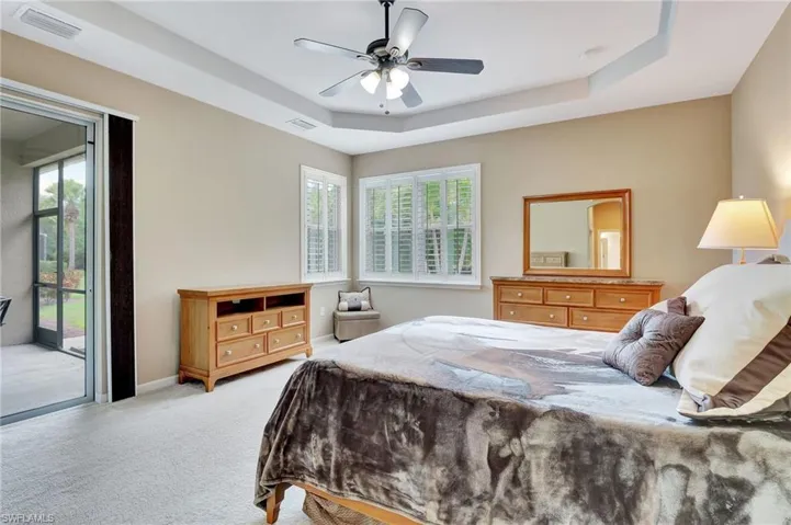 Bedroom featuring ceiling fan, a raised ceiling, and multiple windows