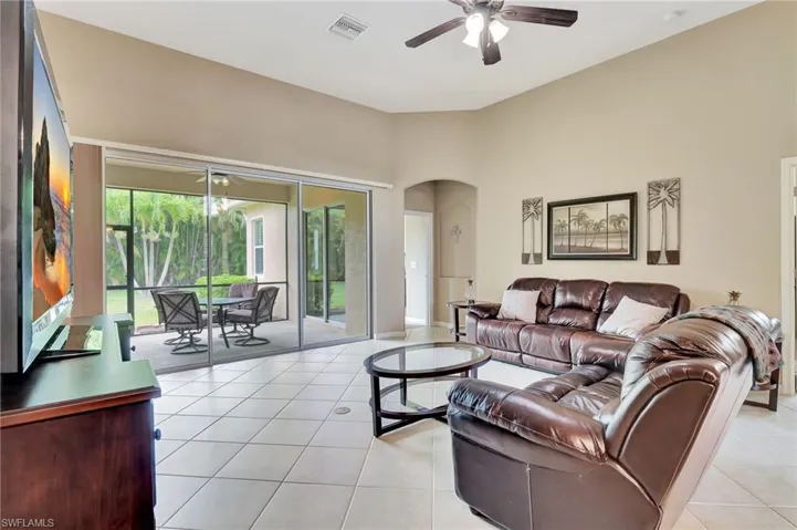 Tiled living room with a healthy amount of sunlight and ceiling fan