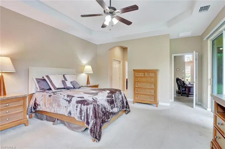 Bedroom with a tray ceiling, ceiling fan, and light colored carpet