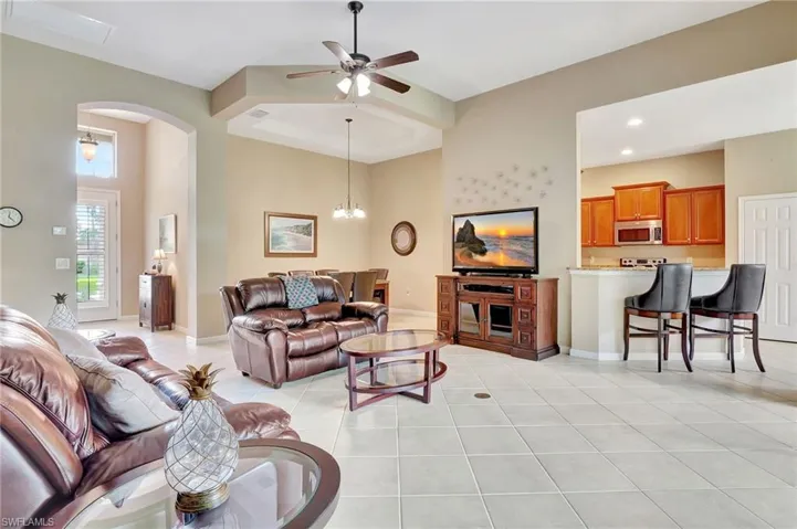 Living room featuring ceiling fan with a towering ceiling, and light tile floors