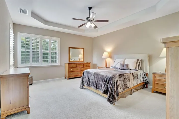 Bedroom featuring ceiling fan, a raised ceiling, and carpet floors