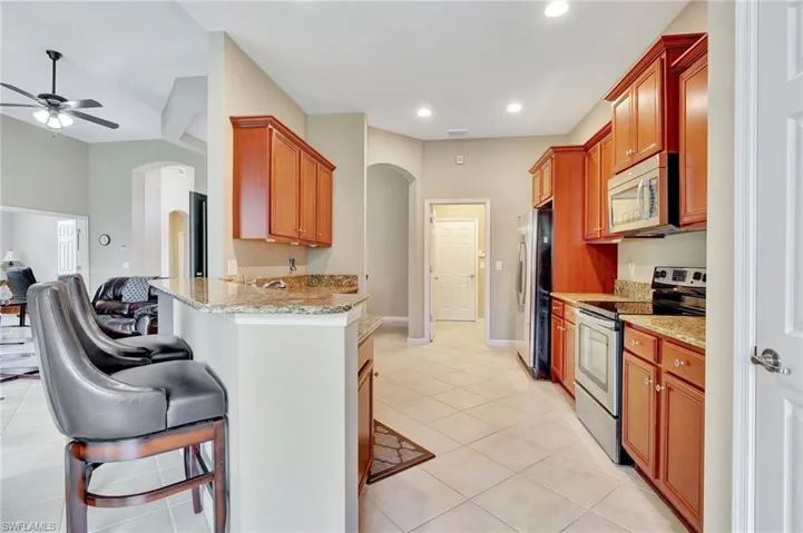 Kitchen featuring a kitchen breakfast bar, stainless steel appliances, kitchen peninsula, and light tile floors