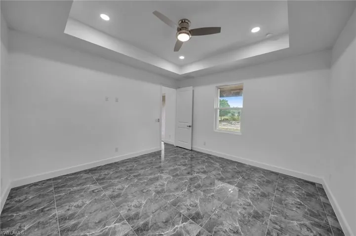 Unfurnished bedroom with recessed lighting, a raised ceiling, a ceiling fan, and baseboards