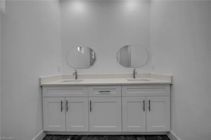 Bathroom featuring double vanity, baseboards, and a sink