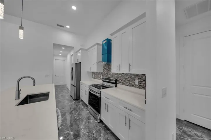 Kitchen featuring stainless steel appliances, a sink, visible vents, marble finish floor, and backsplash
