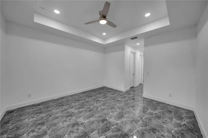 Unfurnished room with a raised ceiling, visible vents, and baseboards