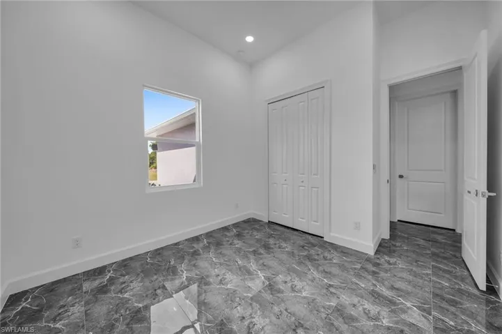 Unfurnished bedroom featuring marble finish floor, a closet, recessed lighting, and baseboards